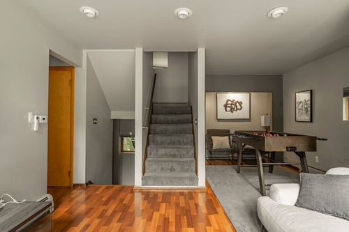 Entry hall with a wood staircase, hardwood floors and a glimpse of a game room beyond