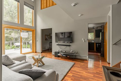 Living room with a wall-mounted TV, gallery wall art and a doorway opening to a hallway