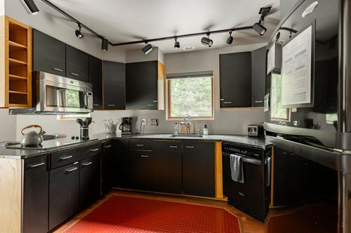 Black cabinet kitchen with wood accent trim and a window over the sink