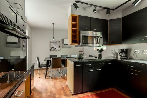 Kitchen with black cabinets, wood open shelving and a peninsula opening to a dining nook