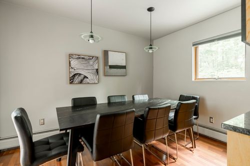 Dining room with a dark wood table, black leather chairs and abstract wall art