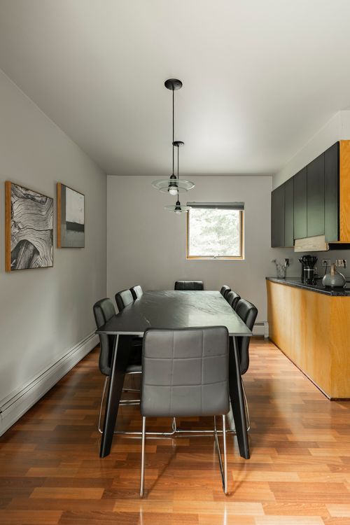 Dining area with a black table and leather chairs beside an open kitchen