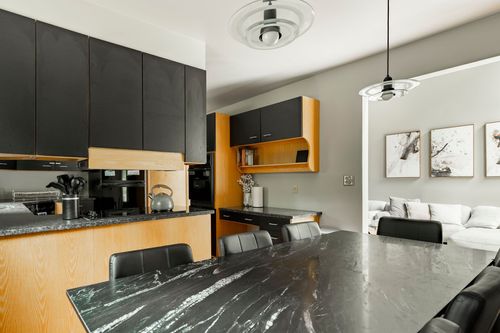 Black marble kitchen island with bar seating opening to a dining table and living room