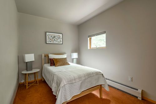Bedroom with a white bed, terracotta carpet and framed art above the headboard
