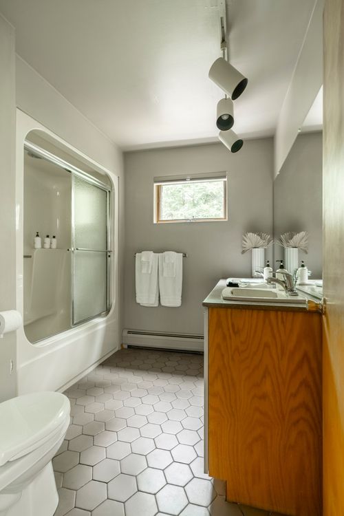 Bathroom with a glass shower enclosure, hexagon tile floor and wood vanity cabinet