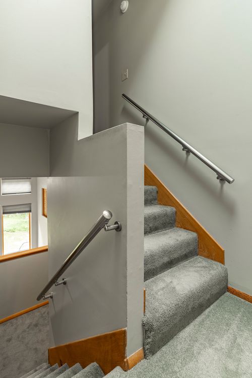 Carpeted staircase with wood trim and brushed metal handrails