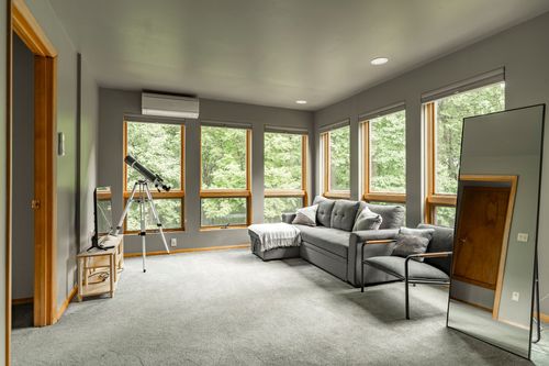 Loft sitting room with a wall of windows, telescope and full-length leaning mirror
