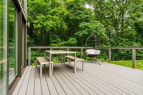 Wood deck with a picnic table and hanging egg chair overlooking the forest