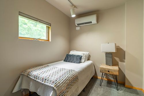 Bedroom with a wall-mounted air conditioning unit and a neatly made twin bed