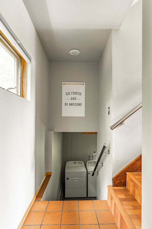Stairwell down to a laundry area with terracotta tile steps and a motivational wall sign