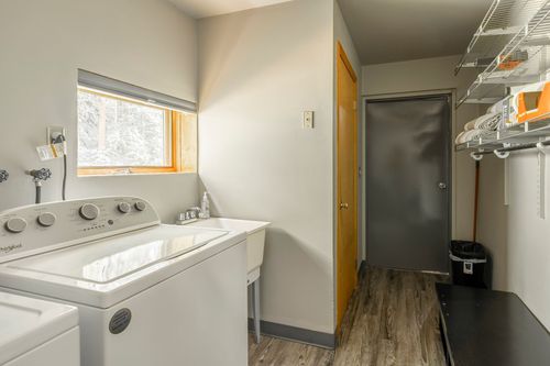 Laundry room with a washer and dryer beside a utility sink and wood-look flooring