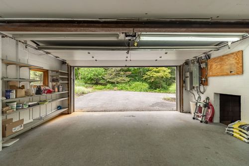 Garage interior with the door open to a wooded driveway and wall storage shelving