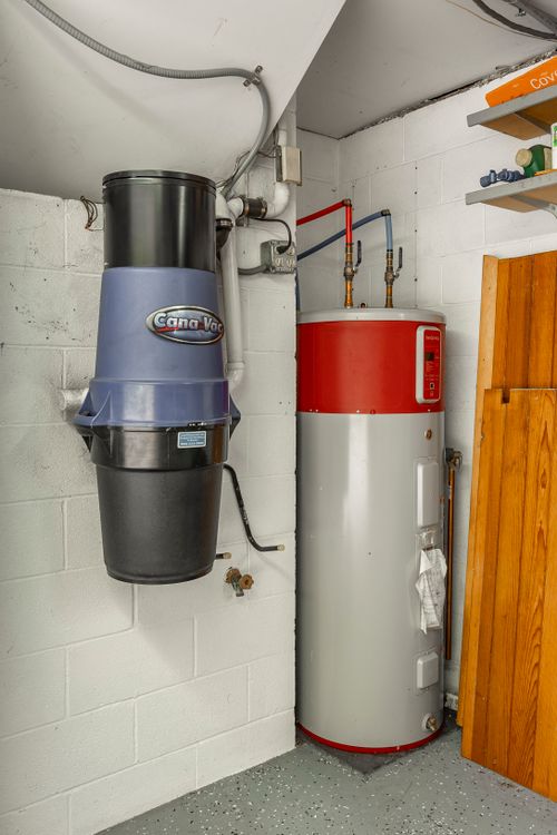 Basement utility area with a central vacuum unit and a red water heater tank
