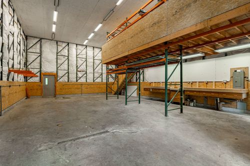 Interior of a barn workshop with a wood mezzanine storage loft and concrete floor