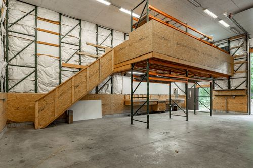 Barn interior with a staircase leading up to an elevated storage mezzanine
