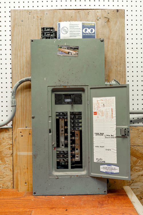 Close-up of a labeled electrical breaker panel mounted on a pegboard wall