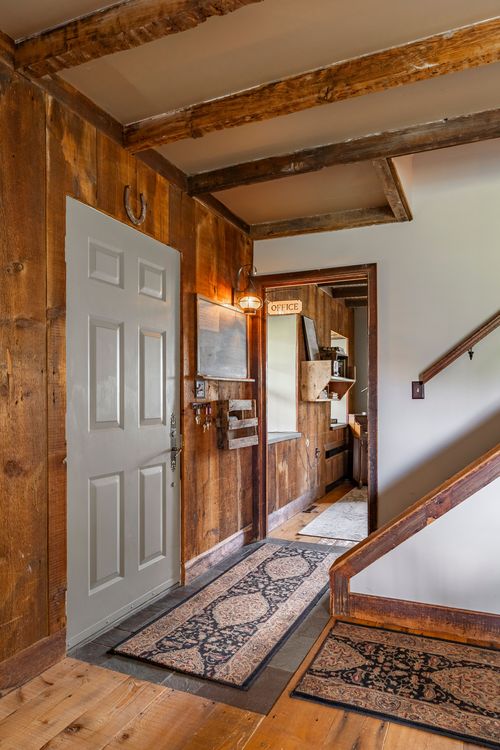 Rustic wood-paneled entryway with barn-style door and layered runner rugs