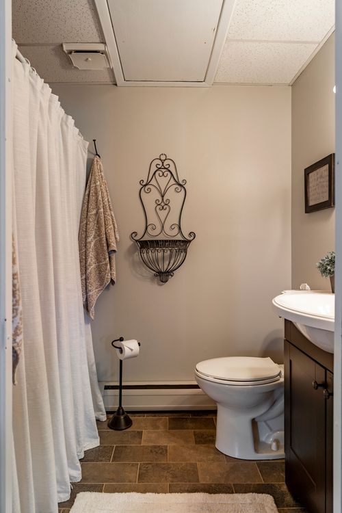 Bathroom with dark wood vanity, oval mirror and towels hung by the shower