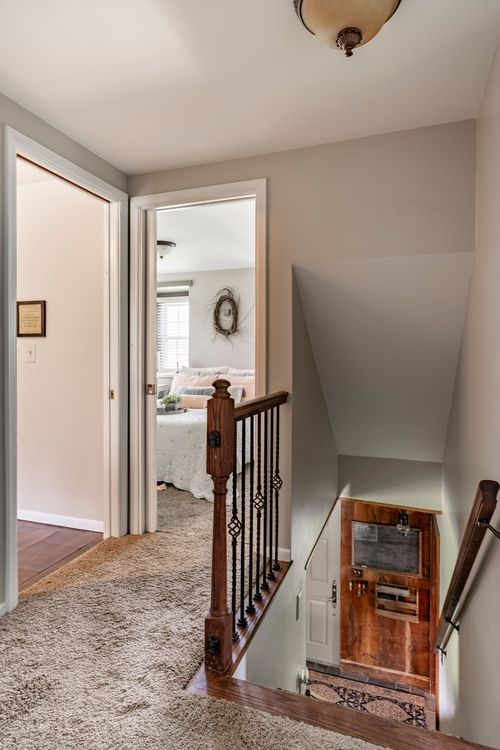 Upstairs hallway overlooking a wood staircase with wrought-iron railing
