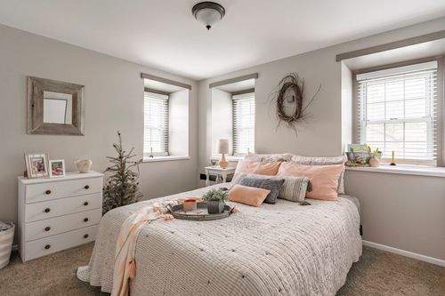 Neutral bedroom with white dresser, small Christmas tree and blush throw pillows