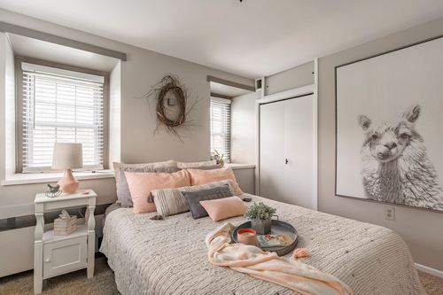 Bedroom with blush and gray bedding, twig wreath accent and llama print artwork