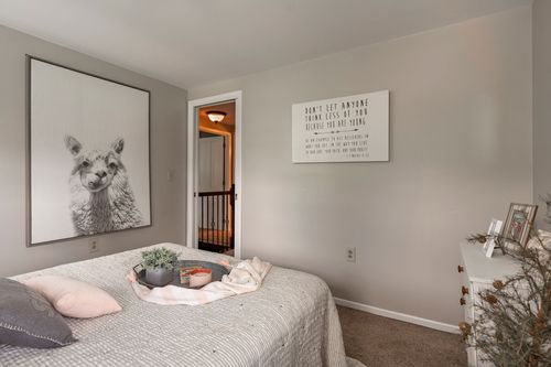 Bedroom with black-and-white llama artwork above the bed and an inspirational wall sign