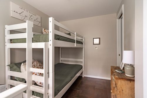 Bunk room with green bedding, dinosaur pillowcase and wood dresser