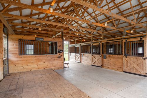 Barn aisle with wood-plank stalls, life is good sign and covered seating area
