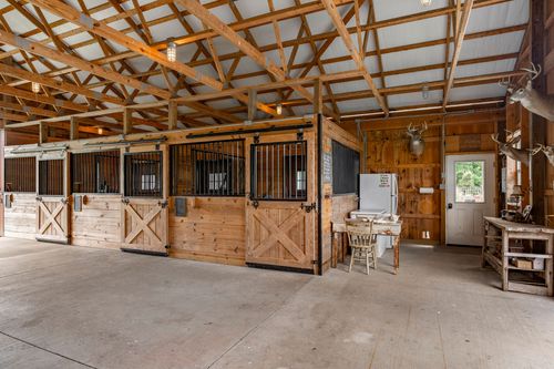 Barn interior with wood horse stalls, taxidermy mount and utility sink area