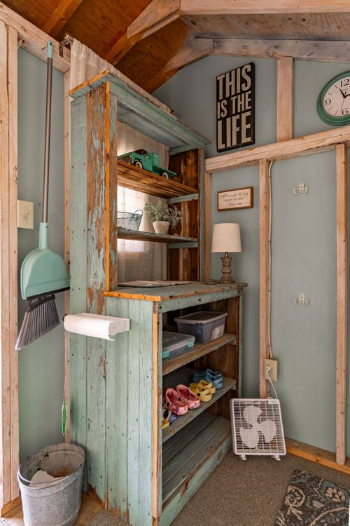 Rustic pool house with weathered green cabinet, storage bins and vintage clock