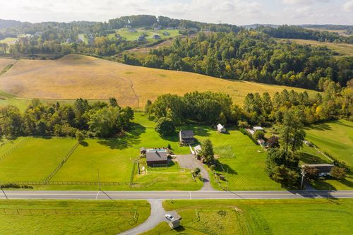 Aerial view of farmland and a wooded ridge with scattered rural homes in the distance