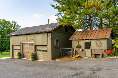 Detached garage with three bays beside a rustic copper-roofed workshop building