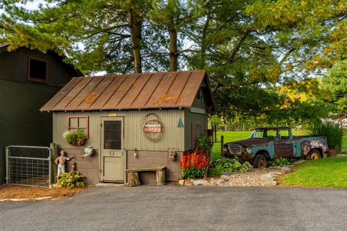 Rustic potting shed with a patina copper roof beside a vintage pickup truck