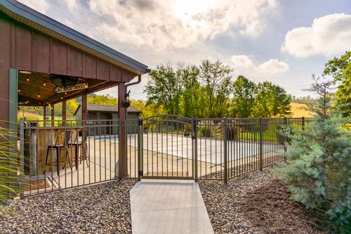 Gated patio walkway leading to a covered outdoor bar area beside a pool