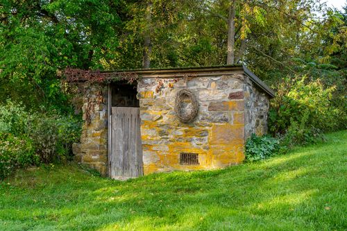 Old stone spring house with a mossy roof and rustic wood plank door