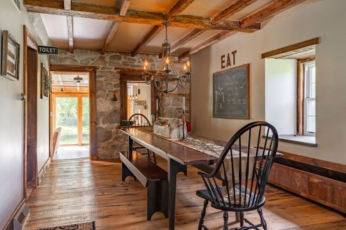 Farmhouse dining room with wood beam ceiling, chandelier and a farm table set for gathering