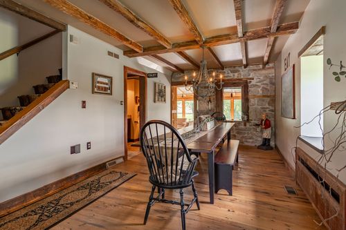 Farmhouse dining room and staircase with exposed beams, wide plank floors and a long wood table