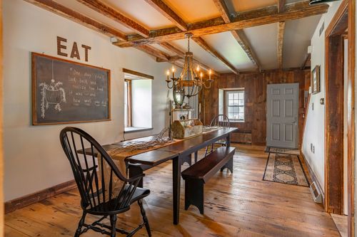 Farmhouse dining room with a chalkboard, EAT wall art and a rustic wood table on wide plank floors