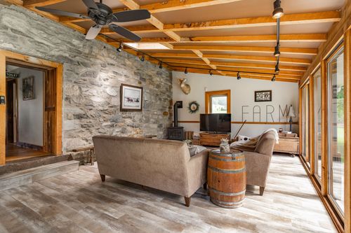 Living room with a stone fireplace wall, wood stove and a whiskey barrel side table