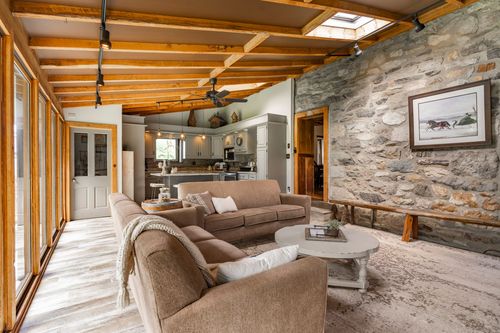 Open living area with a stone wall, skylight and gray cabinetry kitchen beyond
