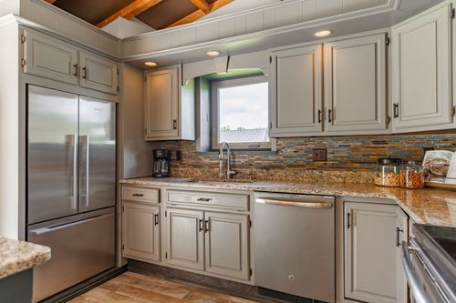Farmhouse kitchen with gray cabinets, stainless appliances and mosaic tile backsplash