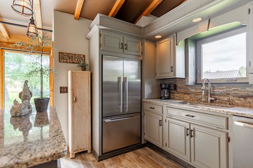Kitchen nook with tall pantry cabinet, stainless fridge and exposed wood beams