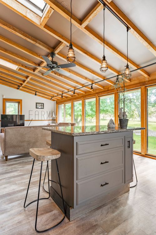 Open living space with vaulted wood-beam ceiling, gray island and skylight