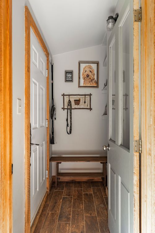 Mudroom hallway with wood-trimmed doors, dog portrait and wall-mounted leash hooks