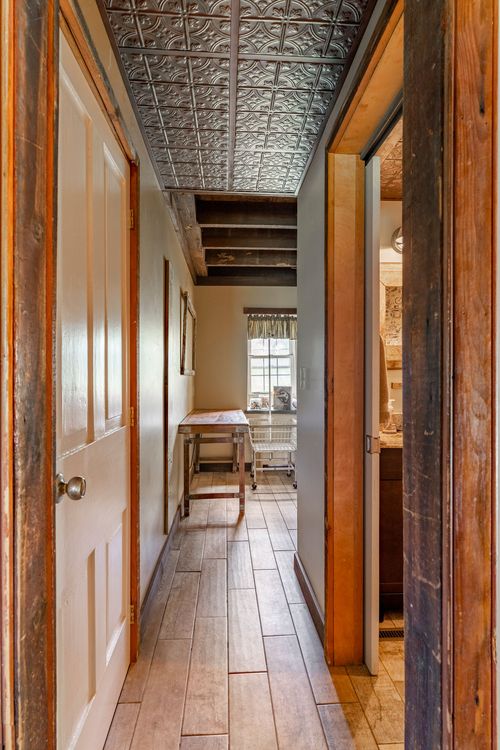 Wood-floored hallway with tin ceiling tiles leading past open doors