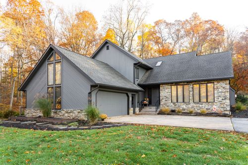 Gray home exterior with vaulted A-frame window, stone base and covered porch