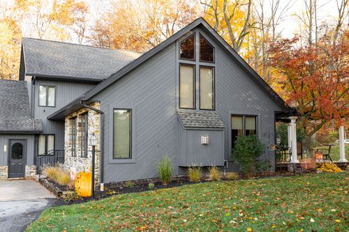 Gray board-and-batten home with peaked gable window and stone accent wall