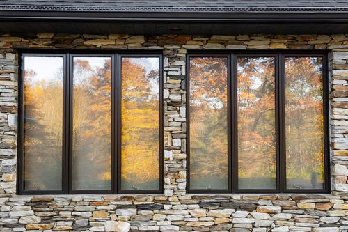 Close-up of tall stone-framed windows reflecting autumn foliage