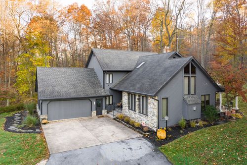 Aerial view of a two-story gray home with stone accents surrounded by fall color
