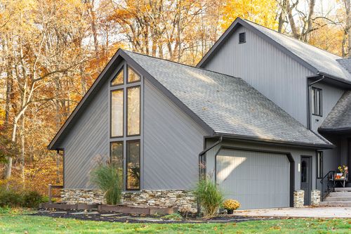 Gray home exterior with vaulted picture window, stone base and two-car garage
